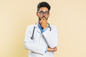Upset scared frightened Indian doctor cardiologist man biting nails, feeling worried nervous about...