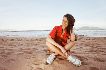 Cheerful Woman on Beach: Smiling, Fashionable and Carefree, Enjoying Vacation by the Ocean at Sunset