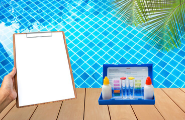 Swimming pool water tester test kit with clipboard in girl hand over clear swimming pool water background, water quality check, pool maintenance and service, water test kit, pool check list and report