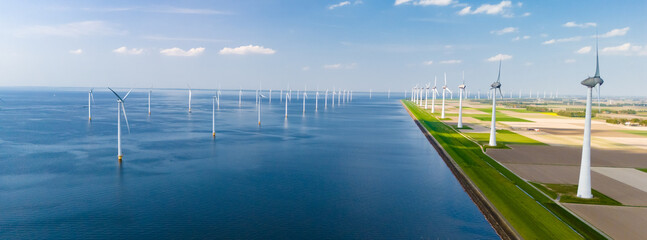 A large body of water in the Netherlands Flevoland is surrounded by numerous wind mills, their blades spinning gracefully in the wind