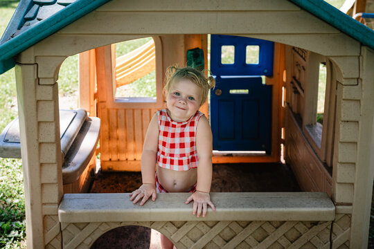 Toddler grins in outdoor playhouse window