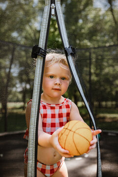 Toddler with basketball on trampoline