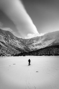 Skier stands in front of Katahdin with spectacular clouds, winter