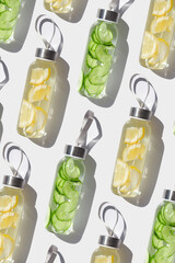 Cleansing, refreshing Lemon, cucumber water drink detox, shadow at sunlight on white, sun glare. Wellness, alkaline diet, eating healthy concept. glass reusable water bottle, top view pattern