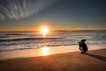 Young girl taking pictures on beautiful beach at sunrise