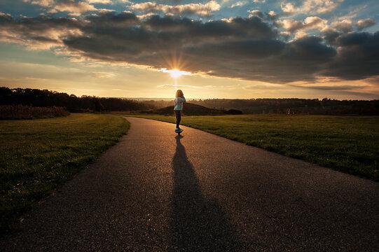 Young girl skateboarding outdoors at sunset
