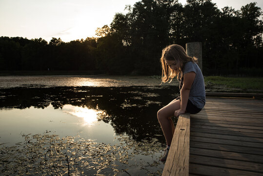 Young girl sitting on dock looking at water