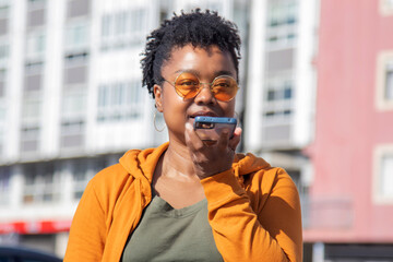 afro woman sending a voice message with the phone on the street
