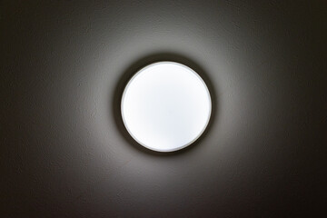 暗い部屋の天井で光る円形の照明器具