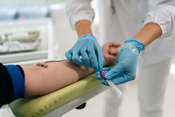 Closeup of unrecognizable female lab assistant in blue medical gloves collecting blood specimen or...