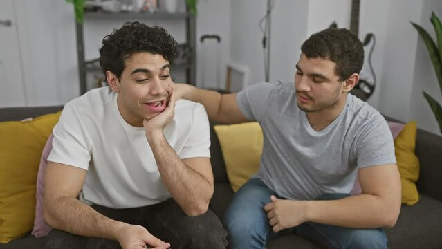 Two men comfort each other in a cozy living room, depicting friendship and support.