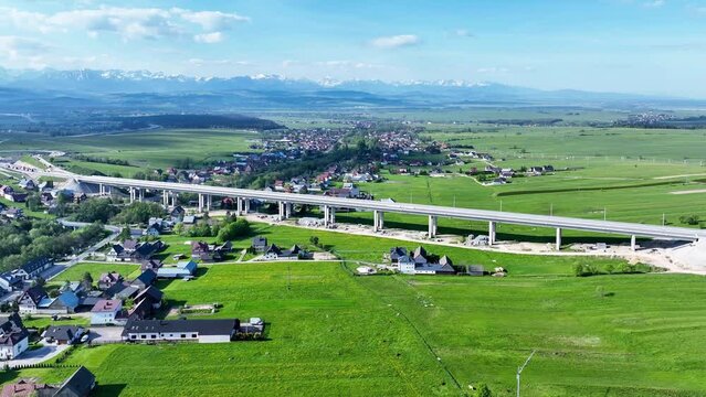 Fragment of highway under construction on Zakopianka road, Poland, over Klikuszowa village, main place of traffic jams. State in May 20204. Tatra Mountains in background. Aerial 4K panning video