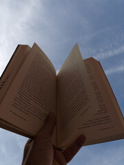 Man lying down and reading a book under the blue sky