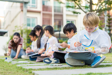 Group of student coloring on painting board outdoors in school garden. 