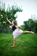 Young Girl Practicing Ballet Moves in a Green Garden at Dusk