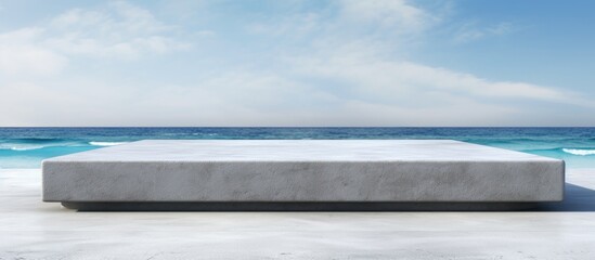 Front view of a grungy grey concrete stone platform podium for cosmetics or products set against a white beach sand background with copy space image
