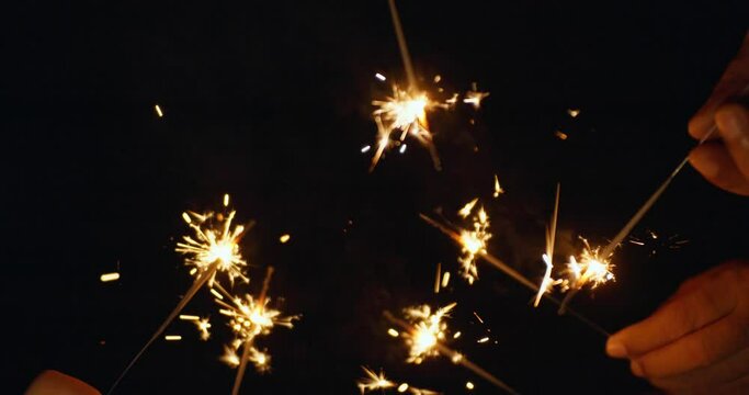 Slow motion shot of sparklers burning on black background.
