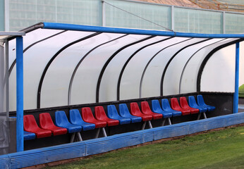 Bench of a football stadium with red and blue seats. No players