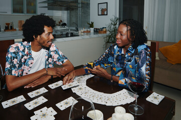 Smiling Black woman spreading tarot cards for her boyfriend