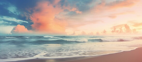 Fototapeta premium A vintage style color filtered copy space image of a tropical beach where soft sand meets the sea and a picturesque sunset sky with clouds create an abstract background This evokes a sense of freedom