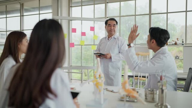 Professional Asian middle age doctor medical teaching and giving lecture to group of medical students in classroom at medical school. Medical students listening and education of medical