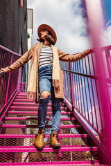 stylish girl in a hat walks down the stairs in the city.