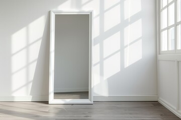 Minimalist white-framed floor mirror in a sunlit room casting shadows on a wooden floor