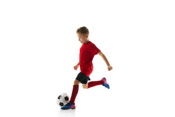 Little athlete boy, training dribbling ball and passing in motion against white studio background....