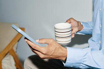 Hands of businessman dinking morning coffee and scrolling social media