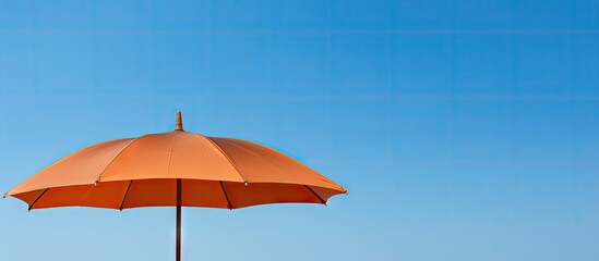 Copy space image of a brown umbrella set against the blue sky