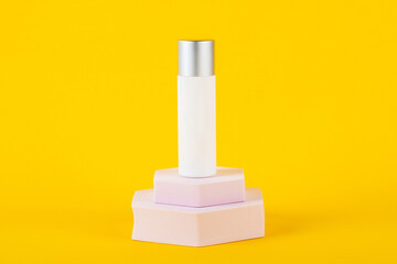 Plastic white tube for cream or lotion. Skin care or sunscreen cosmetic with stylish props on yellow background 