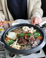 A Korean hot pot with marinated beef, mushrooms, carrots, onions, scallions, and enoki mushrooms,...