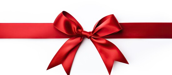 An elegant holiday themed red silk ribbon with a silk red bow isolated on a white background creating a captivating copy space image
