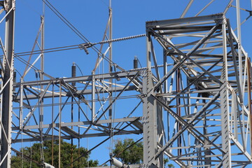 Power lines against a clear blue sky with distant trees