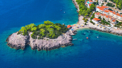 AERIAL: Flying above a sandy beach in Korcula with recliners facing the sea.