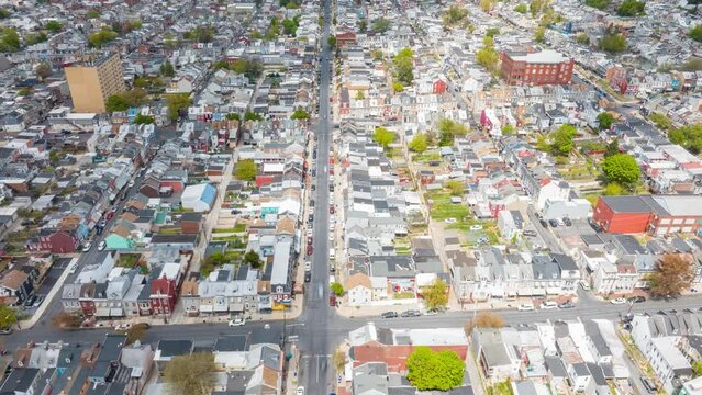 Aerial hyperlapse view of a densely populated American city street lined with tightly packed houses and busy traffic. Top down view of row houses and cars traveling on city streets.
