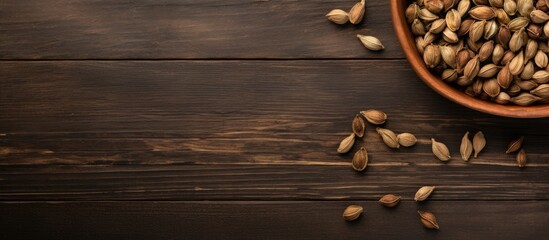 Top down view of a wooden table adorned with a bowl of dry cardamom pods providing ample space for text
