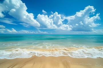 Pristine sandy beach meets turquoise sea under a majestic sky with billowing clouds