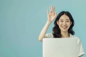 A joyful young woman wearing a casual white T-shirt, smiling and waving while looking over her laptop