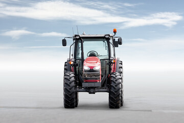 Front view of the red modern wheeled tractor isolated on bright background with sky