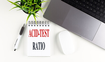 ACID-TEST RATIO text on notebook with laptop, mouse and pen