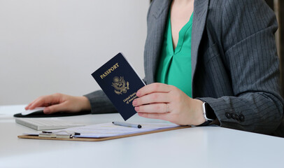 Close up of a caucasian woman holding an American passport at office table