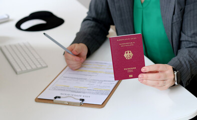 Top view close up of a caucasian woman filling out visa application documents with a German passport