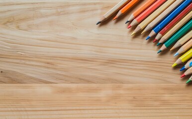 A group of colored pencils on a wooden table. - Powered by Adobe