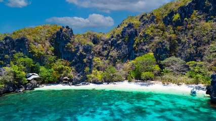 The  white sand beach bathed by a crystal clear water. Entalula island, Bacuit Bay, El Nido,...