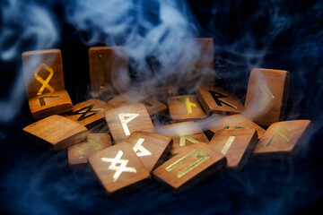 smoke swirls around wooden runes that lie on a black background	

