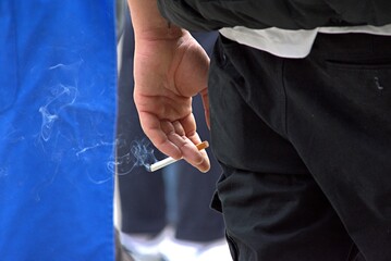 a man stands with a smoking cigarette in his hand