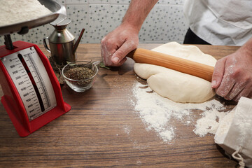 Preparing Homemade Pizza: Kneading Dough on Wooden Table with Toppings Ready