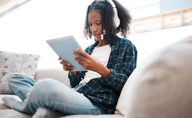 Digital tablet, black girl and headphones on sofa for elearning, education or learning in living...