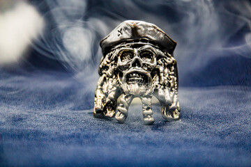 Pirate skull ring shrouded in gray smoke close-up	
